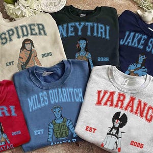May include: Collection of crewneck sweatshirts in various colors, each featuring a character graphic and name from the movie Avatar. The sweatshirts have the names "Spider", "Neytiri", "Jake Sully", "Kiri", "Miles Quaritch", and "Varang".