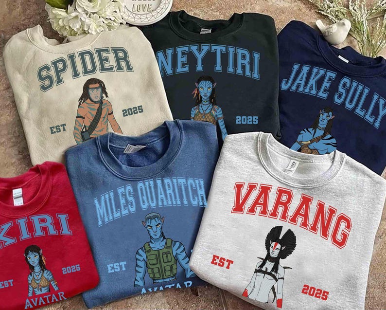 May include: Collection of crewneck sweatshirts in various colors, each featuring a character graphic and name from the movie Avatar. The sweatshirts have the names "Spider", "Neytiri", "Jake Sully", "Kiri", "Miles Quaritch", and "Varang".