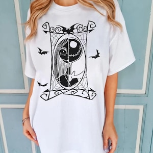 May include: White t-shirt featuring a black and white graphic of Jack Skellington and Sally from The Nightmare Before Christmas. The design is framed by a decorative border with bats and spiderwebs.