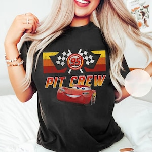 May include: A white ceramic mug with a black handle and the text "But First, Coffee" in a black, bold font. The mug is on a white surface.