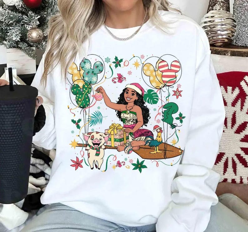 May include: White sweatshirt with a festive cartoon illustration. The design features a character in a Santa hat, surrounded by balloons, gifts, and decorations. Includes a pig, a chicken, and Mickey Mouse-shaped balloons.