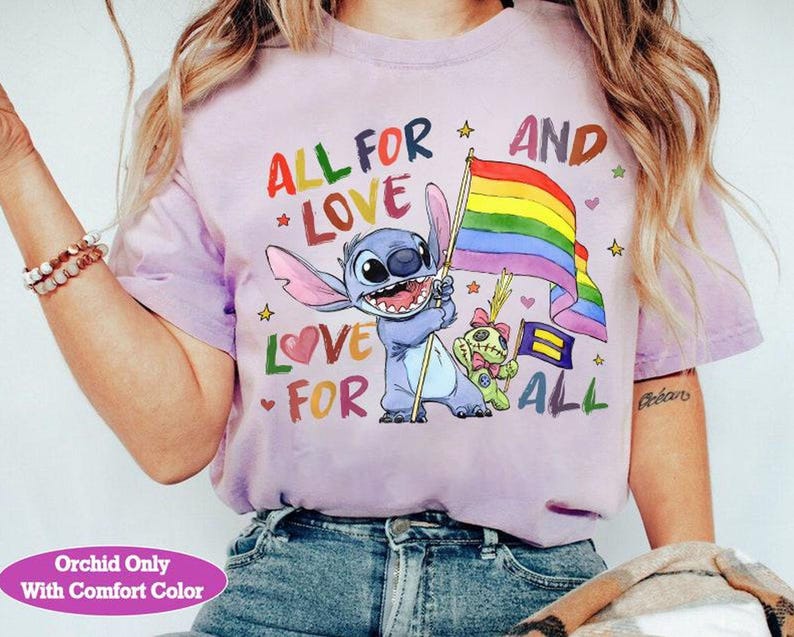May include: A light purple t-shirt with the text "ALL FOR LOVE AND LOVE FOR ALL" and a cartoon character holding a rainbow flag. The shirt also features a smaller character and stars.