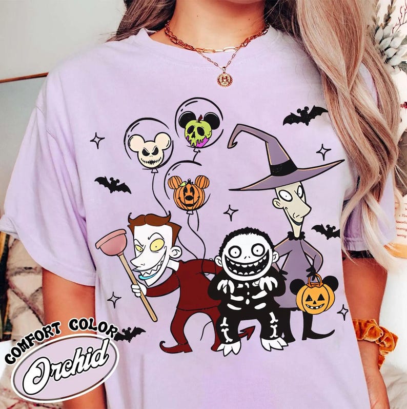 May include: Lilac Comfort Colors t-shirt featuring characters from The Nightmare Before Christmas. The design includes Jack Skellington, Oogie Boogie, and other characters, along with Mickey Mouse-shaped balloons. The shirt has the text "Comfort Color Orchid".