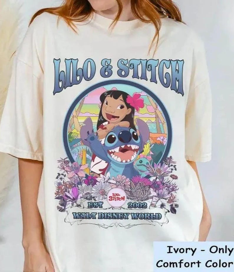 Może przedstawiać: Kremowa koszulka z okrągłą grafiką Lilo i Stitch. Projekt zawiera tekst "Lilo & Stitch", "EST 2002" i "Walt Disney World". Grafika przedstawia Lilo z kwiatem we włosach i Stitcha. Koszulka jest Comfort Color.