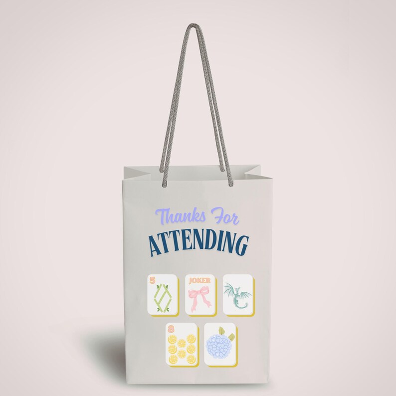 May include: A white gift bag with gray rope handles. The bag features the text "Thanks For ATTENDING" in blue and purple. Below the text are five illustrated tiles with various designs, including a dragon and a bow.