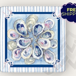 May include: Square decorative item with a watercolor painting of oysters arranged in a circle. The painting has blue, white, and pink hues. The background features blue and white stripes, with a dark blue border. The text "FREE SHIPPING" is in a dark blue bubble.