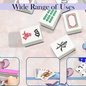 Puede incluir: Azulejos de Mahjong blancos con s&iacute;mbolos rojos y negros esparcidos sobre una superficie con estampado floral. El texto "Wide Range of Uses" est&aacute; en la parte superior. La imagen tambi&eacute;n muestra naipes, domin&oacute;s y otros azulejos de Mahjong.
