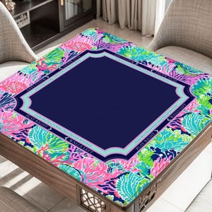 Puede incluir: Una mesa de cartas de madera con un centro azul marino y un borde floral colorido en rosa, verde y azul. La mesa tiene un borde decorativo y est&aacute; rodeada de dos sillas.