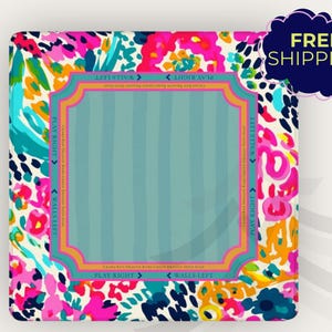 May include: A square, colorful decorative item with a floral pattern in pink, blue, and yellow. The center has a light blue striped design framed by a decorative border. Text includes "PLAY RIGHT" and "WALLS LEFT".