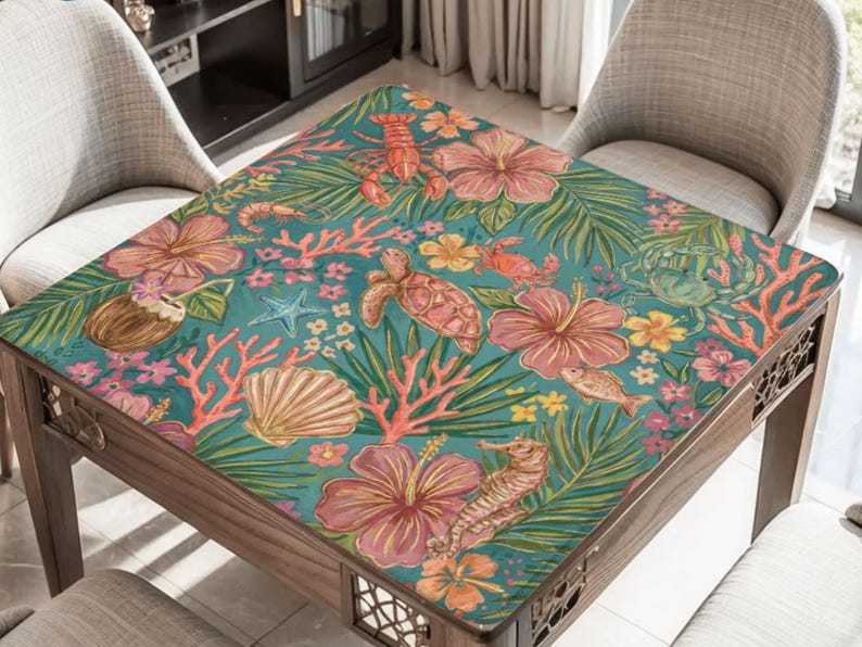 May include: A wooden table with a teal surface featuring a tropical design. The design includes pink hibiscus flowers, sea creatures like turtles and seahorses, and coral. The table is surrounded by two grey chairs.