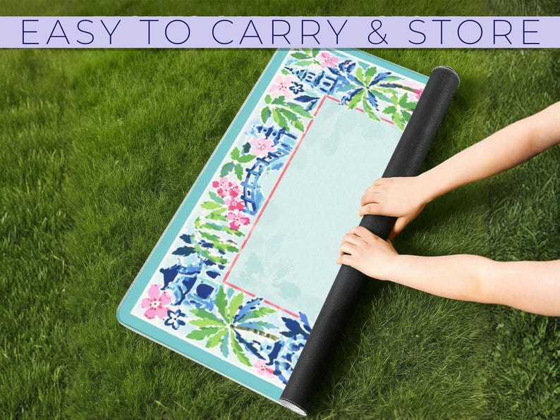 May include: A rolled-up yoga mat with a floral and palm tree design is held by two hands on a grassy surface. The mat has a light blue background with pink and blue floral accents. The text "EASY TO CARRY & STORE" is at the top.