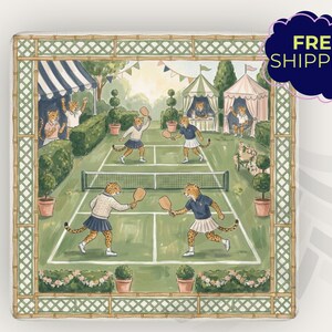 May include: Square decorative art print featuring a tennis match scene with cheetahs playing on a green court. The print has a bamboo-style border and includes tents, spectators, and potted plants. The color palette is soft, with greens, blues, and creams.