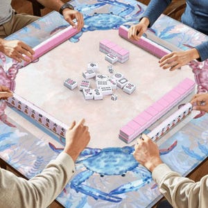 Puede incluir: Una mesa de Mahjong cuadrada con un dise&ntilde;o de cangrejo y oc&eacute;ano. Los jugadores est&aacute;n sentados alrededor, sosteniendo estantes de fichas rosas. Las fichas y dados de Mahjong blancos est&aacute;n en el centro, listos para jugar.
