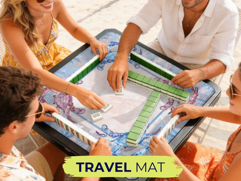 May include: A square mahjong travel mat with a blue crab design. The mat is surrounded by players holding mahjong tiles. The text "TRAVEL MAT" is displayed in a yellow banner at the bottom of the image.