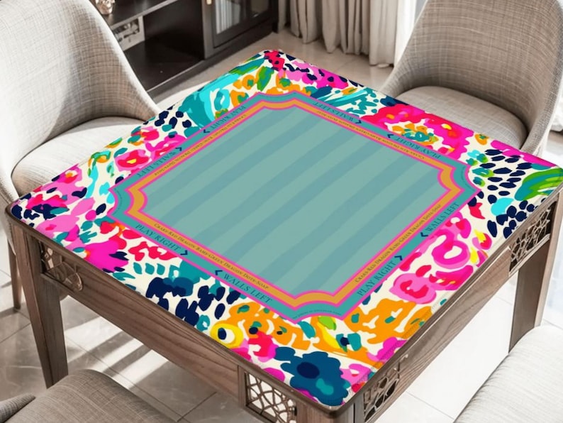 May include: A wooden table with a colorful floral patterned top. The top features a central light blue section with vertical stripes, framed by a decorative border. The floral pattern includes pink, blue, and yellow accents.