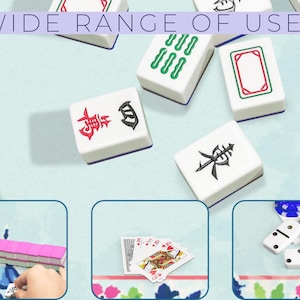 Pu&ograve; includere: Tessere di Mahjong bianche con simboli rossi, verdi e neri sono sparse su una superficie azzurra. Il testo "WIDE RANGE OF USES" &egrave; in alto. L'immagine mostra anche carte da gioco, domino e un set di Mahjong.
