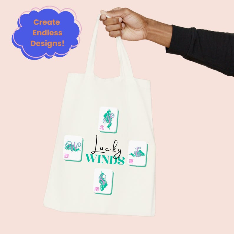 May include: Cream-colored tote bag featuring four Mahjong tiles with teal and pink accents. The text "Lucky Winds" is centered below the tiles. A blue cloud-shaped graphic with the text "Create Endless Designs!" is in the upper left corner.