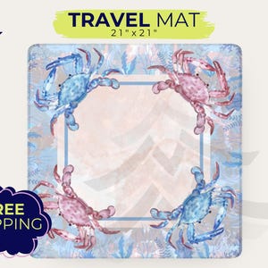 May include: Square travel mat with a watercolor design featuring four crabs in shades of blue and pink. The mat is 21 x 21 inches and has a light blue border. The background has a light blue and peach chevron pattern.