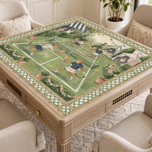 May include: A square wooden coffee table with a painted tennis court scene on the tabletop. The artwork features cheetahs playing tennis on a green court, surrounded by a decorative border. The table is light brown and has four legs.