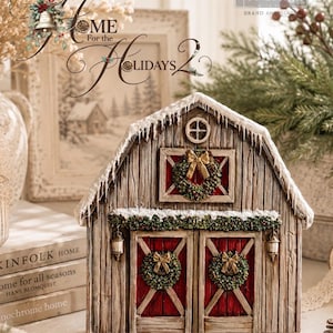 Può includere: Un ornamento decorativo a forma di fienile con rivestimento in finto legno invecchiato, doppie porte rosse e un tetto innevato. La struttura è decorata con tre ghirlande verdi con fiocchi dorati, una piccola finestra circolare e due lanterne appese.
