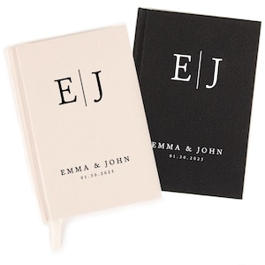 May include: Two personalized notebooks, one cream and one black, are displayed. Each notebook features the initials "E | J" and the names "EMMA & JOHN" with the date "01.30.2025" printed below, suggesting a wedding or anniversary theme.