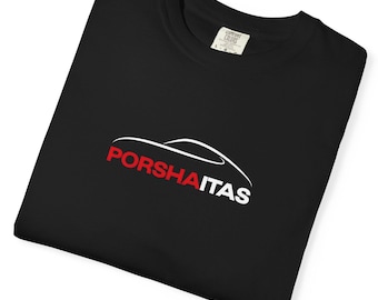 May include: Black t-shirt with a white and red graphic. The graphic features a car outline above the word "PORSHAITAS" in red and white font. The shirt is made of a soft material.