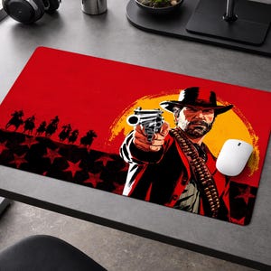 May include: Red mousepad featuring a Western-themed illustration. The design includes a man with a gun, a sunset, and silhouettes of riders. A white mouse sits on the pad.
