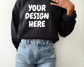 May include: Black sweatshirt with the text "YOUR DESIGN HERE" in white block letters. The sweatshirt is paired with light blue denim shorts. The image is a product shot, likely for a clothing item.