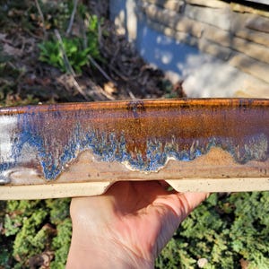 May include: A white ceramic mug with a black handle and the text "But First, Coffee" in a black, bold font. The mug is on a white surface.