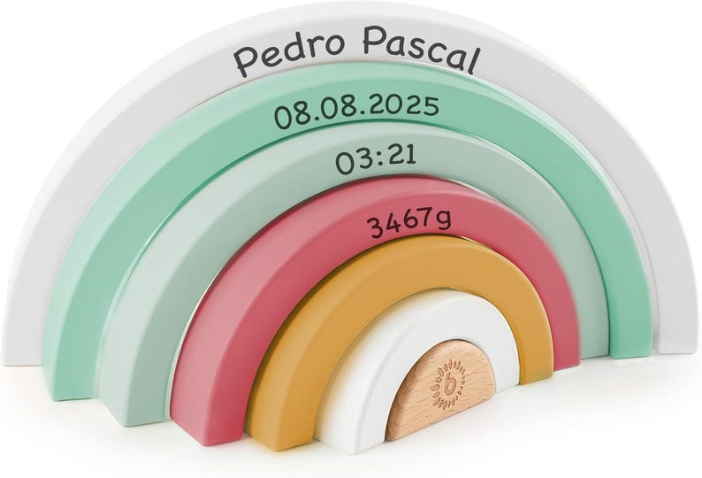 May include: A decorative wooden rainbow stacker featuring six nested arches in white, mint green, dusty rose, and mustard yellow. The arches are printed with the text Pedro Pascal, 08.08.2025, 03:21, and 3467g. The smallest center piece is natural wood.