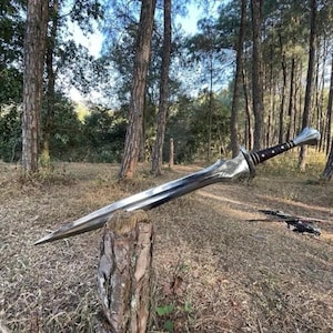 Puede incluir: Una espada plateada grande con una empuñadura detallada y un mango marrón oscuro descansa sobre un tocón de árbol en un entorno forestal. La hoja es larga y curvada, reflejando la luz del sol. El diseño de la espada sugiere un tema de fantasía o histórico.