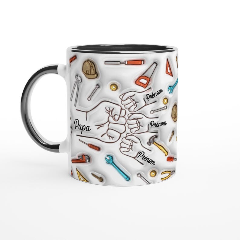 Puede incluir: Taza de cer&aacute;mica blanca con asa y borde negros. La taza presenta un dise&ntilde;o de manos chocando los pu&ntilde;os, rodeadas de herramientas como martillos, sierras y llaves. La palabra "Papa" est&aacute; escrita en la taza, junto con la palabra "Pr&eacute;nom".