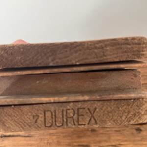 May include: A stack of three rectangular wooden blocks with a natural brown grain. The bottom block features the word DUREX and the number 7 stamped into the wood surface in a clear, dark, sans-serif font. The edges of the blocks are visible.