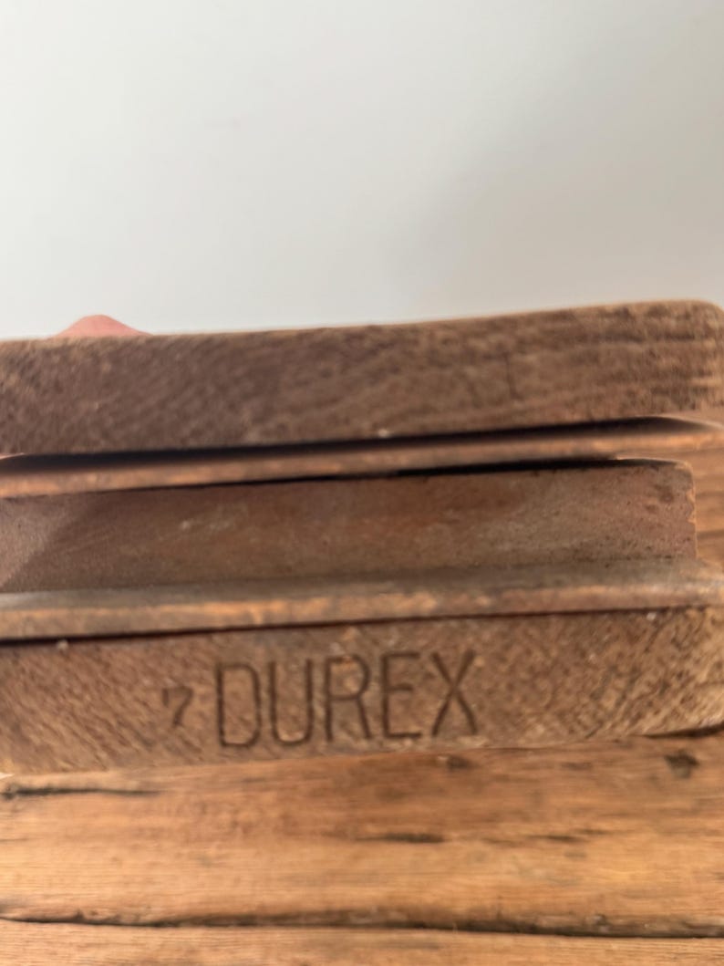 May include: A stack of three rectangular wooden blocks with a natural brown grain. The bottom block features the word DUREX and the number 7 stamped into the wood surface in a clear, dark, sans-serif font. The edges of the blocks are visible.