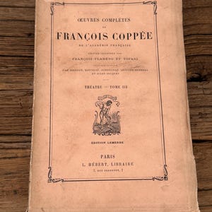 May include: A vintage softcover book titled Oeuvres Complètes de François Coppée, Théâtre Tome III. The beige cover features black typography, a central illustration of a person working in a field, and the publisher details L. Hébert, Libraire.