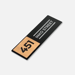 May include: A rectangular black and copper address sign. The sign features the number "451" in a copper-colored rectangle, and the text "INKO STREET" in white on a black background.