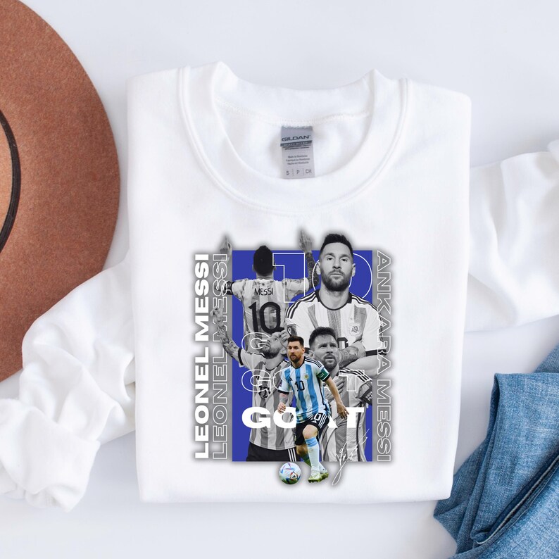 May include: White sweatshirt with a design featuring Lionel Messi. The design includes multiple images of the footballer, with the text "LEONEL MESSI" and "ANKARA MESSI" in a vertical layout, and the word "GO".