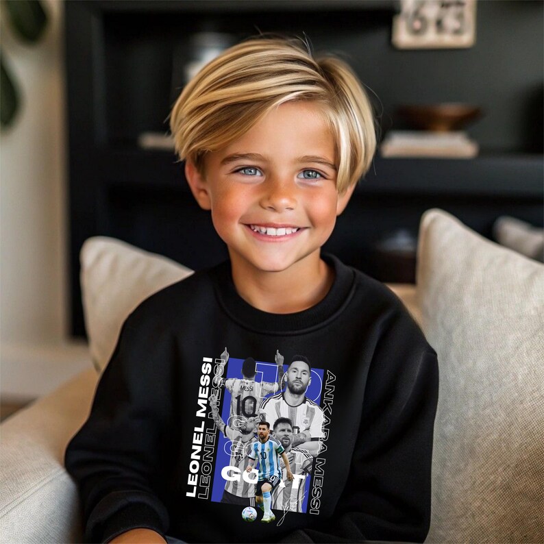 May include: A child wearing a black sweatshirt with a graphic of Lionel Messi. The graphic includes images of Messi in different poses, with text that reads "LEONEL MESSI" and "ANKARA MESSI".