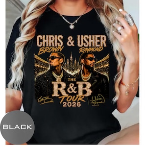 May include: A black t-shirt featuring a graphic print of Chris Brown and Usher. The text reads CHRIS & USHER, BROWN RAYMOND, THE R&B TOUR 2026, along with two signatures. The design includes gold-toned lettering and a city skyline background.