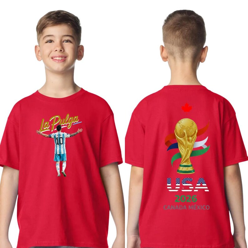 May include: Red t-shirt featuring a soccer player with the text "La Pulga" on the front. The back of the shirt displays the FIFA World Cup trophy, flags, and the text "USA 2026 CANADA MEXICO".