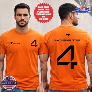 May include: Orange t-shirt with black graphics. The front features the number 4 and the word "NOR" with a logo. The back displays "NORRIS" and the number 4. The shirt is labeled "MADE IN USA".