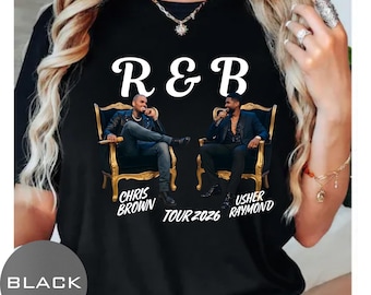 May include: A black t-shirt featuring the white text R&B above two men sitting in ornate gold chairs. The text below reads CHRIS BROWN, TOUR 2026, and USHER RAYMOND. The graphic shows Chris Brown in a leather jacket and Usher in a dark blazer.