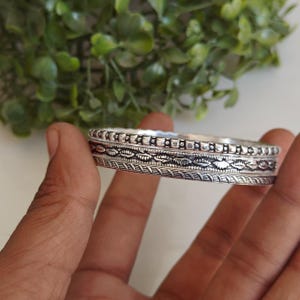 Könnte beinhalten: Eine weiße Keramik-Tasse mit schwarzem Henkel und dem Text "But First, Coffee" in fetter, schwarzer Schrift. Die Tasse ist mit einer dunklen Flüssigkeit gefüllt, wahrscheinlich Kaffee, und steht auf einer hellen Oberfläche.