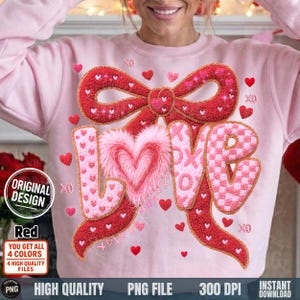 Puede incluir: Sudadera rosa claro con un lazo rojo y la palabra "LOVE". Las letras están decoradas con corazones y un corazón rosa esponjoso. Pequeños corazones rojos y símbolos "XO" están dispersos por el diseño.