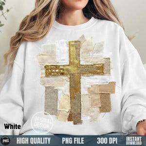 May include: White sweatshirt featuring a gold cross design made of various fabric patches. The cross has a sequined center and is surrounded by beige, cream, and white fabric pieces. The words "Original Design" are printed on the sweatshirt.