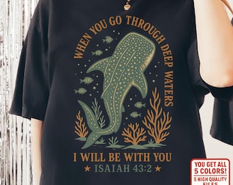 May include: Black t-shirt featuring a whale shark illustration in shades of green and brown, surrounded by fish and coral. The shirt includes the text "WHEN YOU GO THROUGH DEEP WATERS, I WILL BE WITH YOU, ISAIAH 43:2".