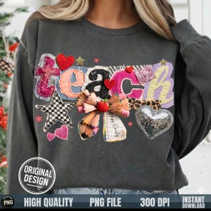 Peut inclure: Sweat-shirt gris foncé avec le mot "TEACH" dans un design patchwork. Les lettres sont décorées de cœurs, d'étoiles et d'une fleur de crayon. Un cœur argenté et une étoile à carreaux noirs et blancs sont également présents.