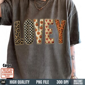 May include: A grey t-shirt with the word "LOVEY" in a patchwork design. The letters feature leopard print, a black and white checkerboard, jack-o'-lanterns, and hearts. The shirt has short sleeves and a relaxed fit. The image also includes text about colour and file type.