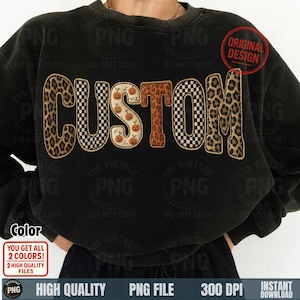May include: Black sweatshirt with the word "CUSTOM" in a mix of patterns. The letters feature leopard print, checkerboard, and pumpkin designs. A red circle with "ORIGINAL DESIGN" is in the upper right corner.