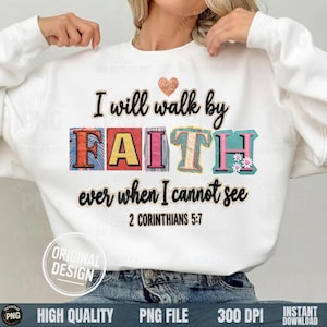 Può includere: Felpa bianca con la scritta "I will walk by FAITH ever when I cannot see 2 Corinthians 5:7". La parola "FAITH" è in lettere a blocchi colorate. Una piccola grafica a forma di cuore è sopra il testo.